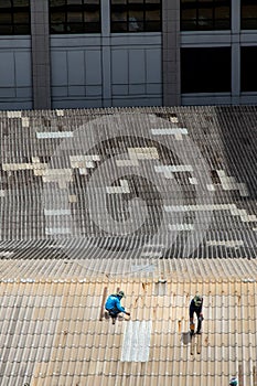 Two handyman workers repairing tiles on the damaged factory roof