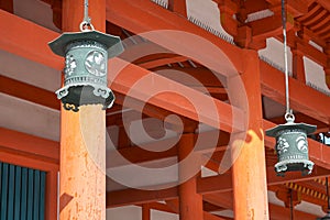 Hanging copper lanterns on the background of vermilion columns. Heian-jingu Shrine. Kyoto. Japan