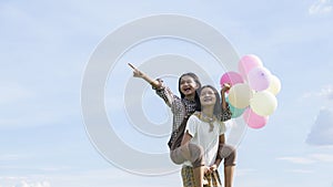 Two happy Asain girl holding balloon with blue sky background