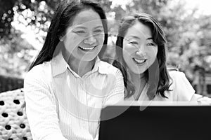 Two happy Asian women together using laptop computer