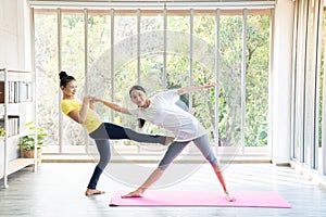 Two happy asian women in yoga poses in yoga studio with natural light setting scene / exercise concept / yoga practice / copy