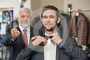 Two happy atractive elegant men choosing clothes for special occaision.