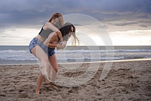 Two happy and attractive young Asian Chinese women girlfriends or sisters having fun playing in the sand on sunset beach in beauti