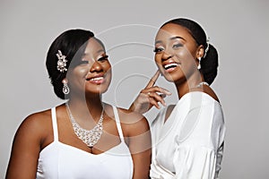 Two happy and beautiful black skin woman. Charming young bride in wedding dress and jewelry.