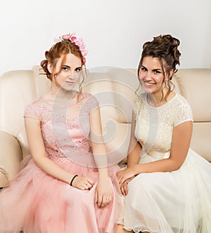 Two happy beautiful young women in elegant dresses, tender history