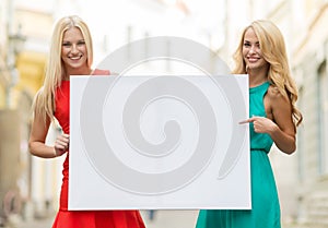 Two happy blonde women with blank white board