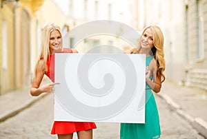 Two happy blonde women with blank white board