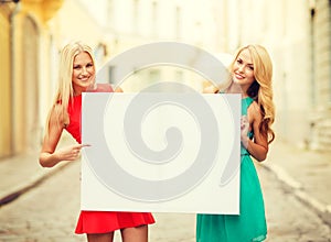 Two happy blonde women with blank white board
