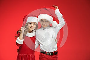 Two happy boy and girl in santa claus hats with gift boxes at studio