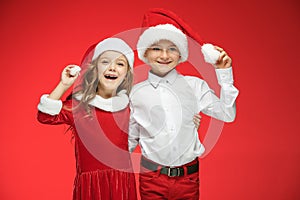 Two happy boy and girl in santa claus hats with gift boxes at studio