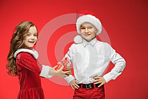 Two happy boy and girl in santa claus hats with gift boxes at studio