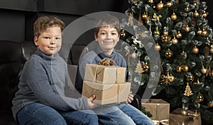 Two happy boys with christmas gift near Christmas tree