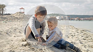 Two happy boys playin by the sea, enjoying building the sand castle. Concept of tourism, travel, summer vacation