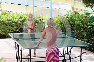 Two happy boys playing ping pong outdoors