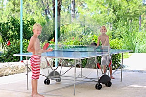 Two happy boys playing ping pong outdoors