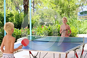 Two happy boys playing ping pong outdoors