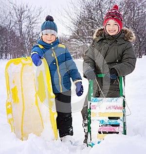 Two happy boys on sled and Skis in winter outdoors