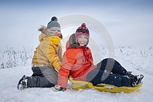 Two happy boys on sled and Skis in winter outdoors