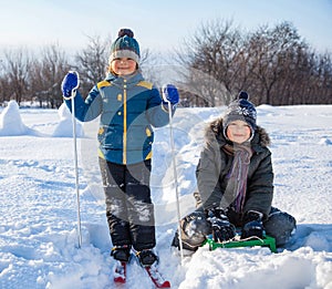 two happy boys on sled and Skis in winter outdoors