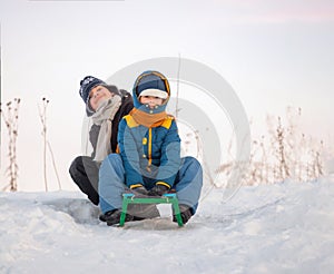 Two happy boys on sled in winter outdoors
