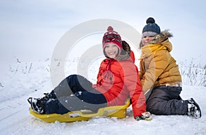 Two happy boys on sled in winter outdoors