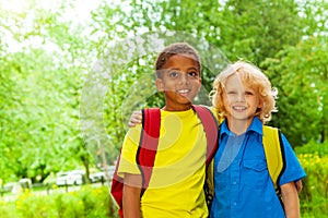 Two happy boys wearing school bags stand together