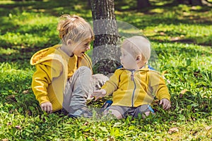 Two happy brothers in yellow sweatshirts in the autumn park