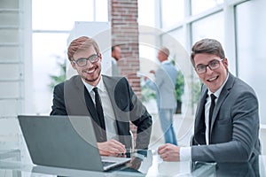 Two happy businessmen sitting at an office Desk