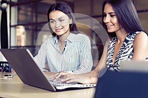 Two happy businesswomen coworking with a laptop in a desktop at office.