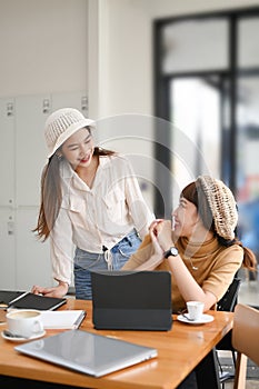 Two happy businesswomen coworking with a laptop in office.