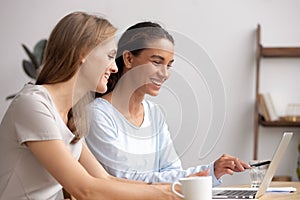 Two happy businesswomen work together collaborate on laptop in office