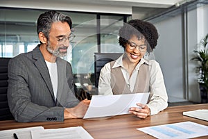 Two happy busy diverse business man and woman working at meeting with documents.