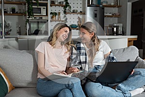 Two happy carefree young women business partners and owners, friends sitting on the sofa are happy because they have just tried