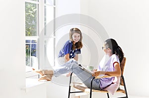 Two happy casual women relaxing with hot drink in new home