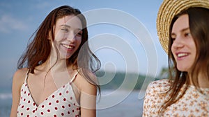 Two happy caucasian girls walking, talking at tropical beach on paradise island. Joyful models go, smile at seaside