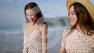 Two happy caucasian girls walking, talking at tropical beach on paradise island. Joyful models going, smiling at seaside