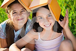 Two happy child girls studying on grass