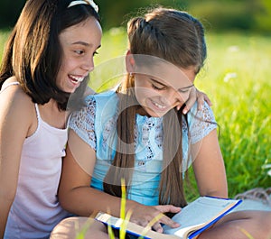 Two happy child girls studying on grass