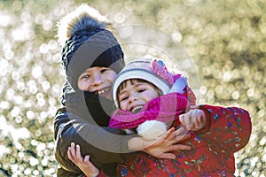 Two happy children boy and girl playing outdoors in sunny winter