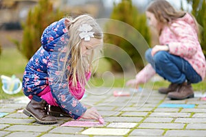 Two happy children drawing with colorful chalks on a sidewalk. Summer activity for small kids.