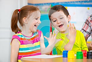 Two happy children drawing with colorful paints