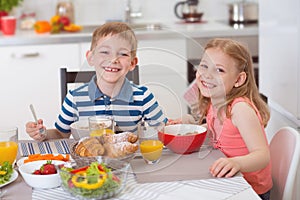 Two happy children having breakfast in kitchen