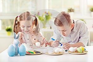 Two happy children having fun during painting eggs for easter in