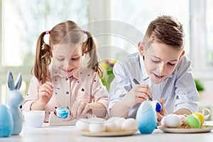 Two happy children having fun during painting eggs for easter in