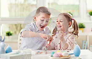 Two happy children having fun during painting eggs for easter in