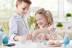 Two happy children having fun during painting eggs for easter in