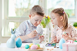 Two happy children having fun during painting eggs for easter in
