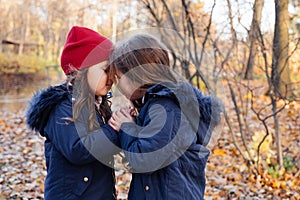 Two happy children hugging in autumn park. Close up sunny lifestyle fashion portrait of two beautiful caucasian girls outdoors,wea