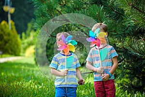 Two happy children playing in garden with windmill pinwheel. Ado