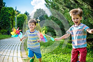 Two happy children playing in garden with windmill pinwheel. Ado